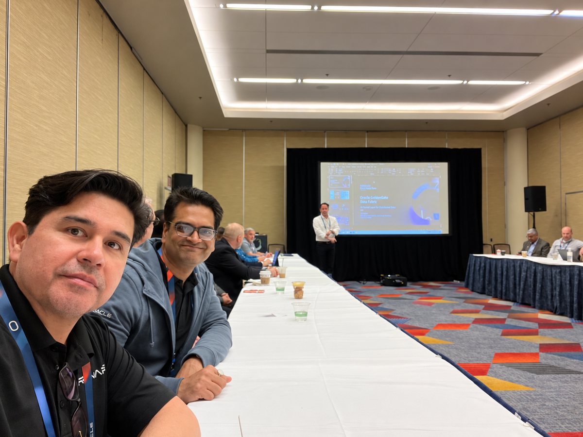 RENAPS team members seated at a long table during a GoldenGate session, with a speaker presenting in front of a screen